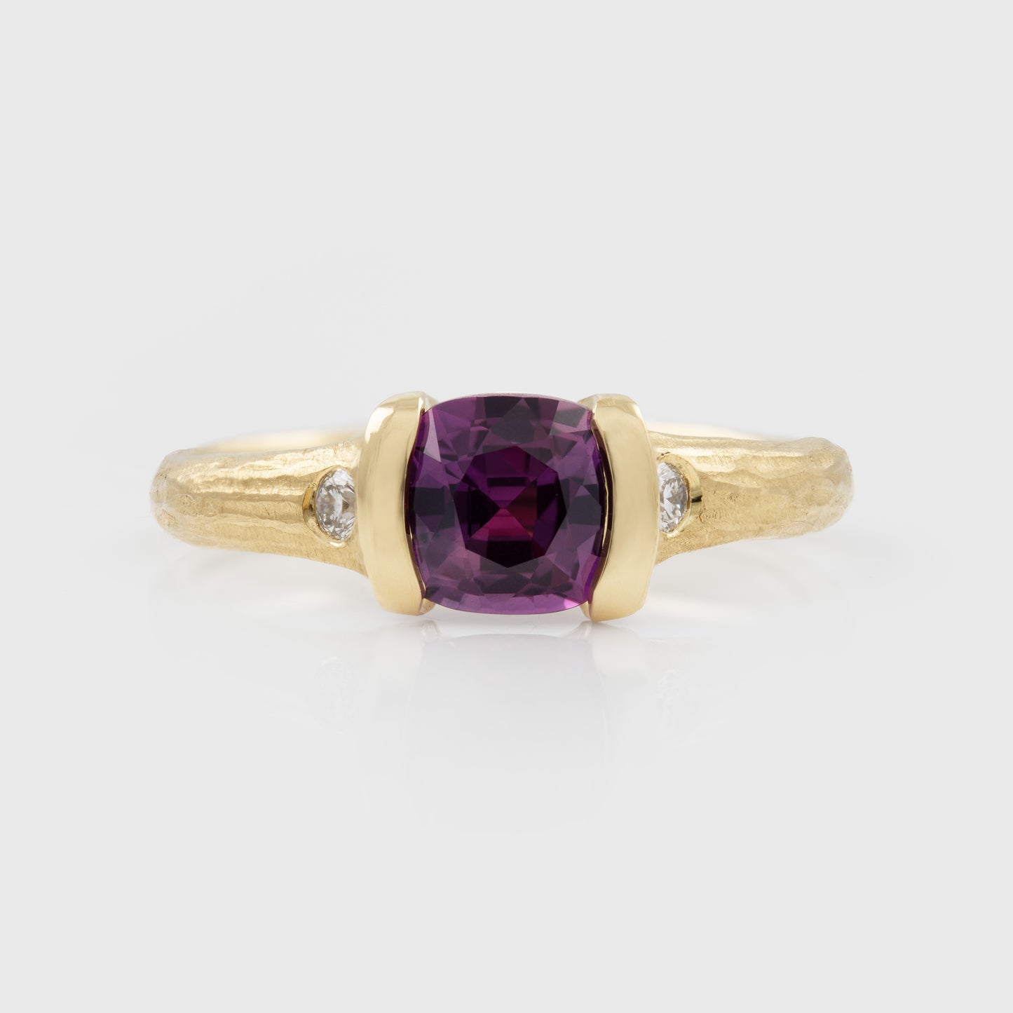 Gold ring with a purple gemstone and small diamonds on a white background