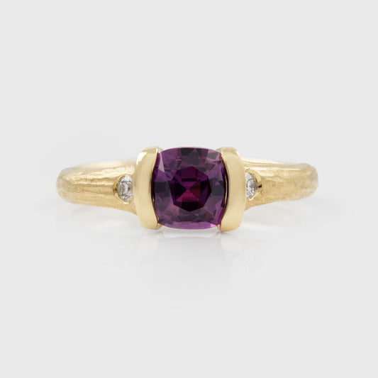 Gold ring with a purple gemstone and small diamonds on a white background