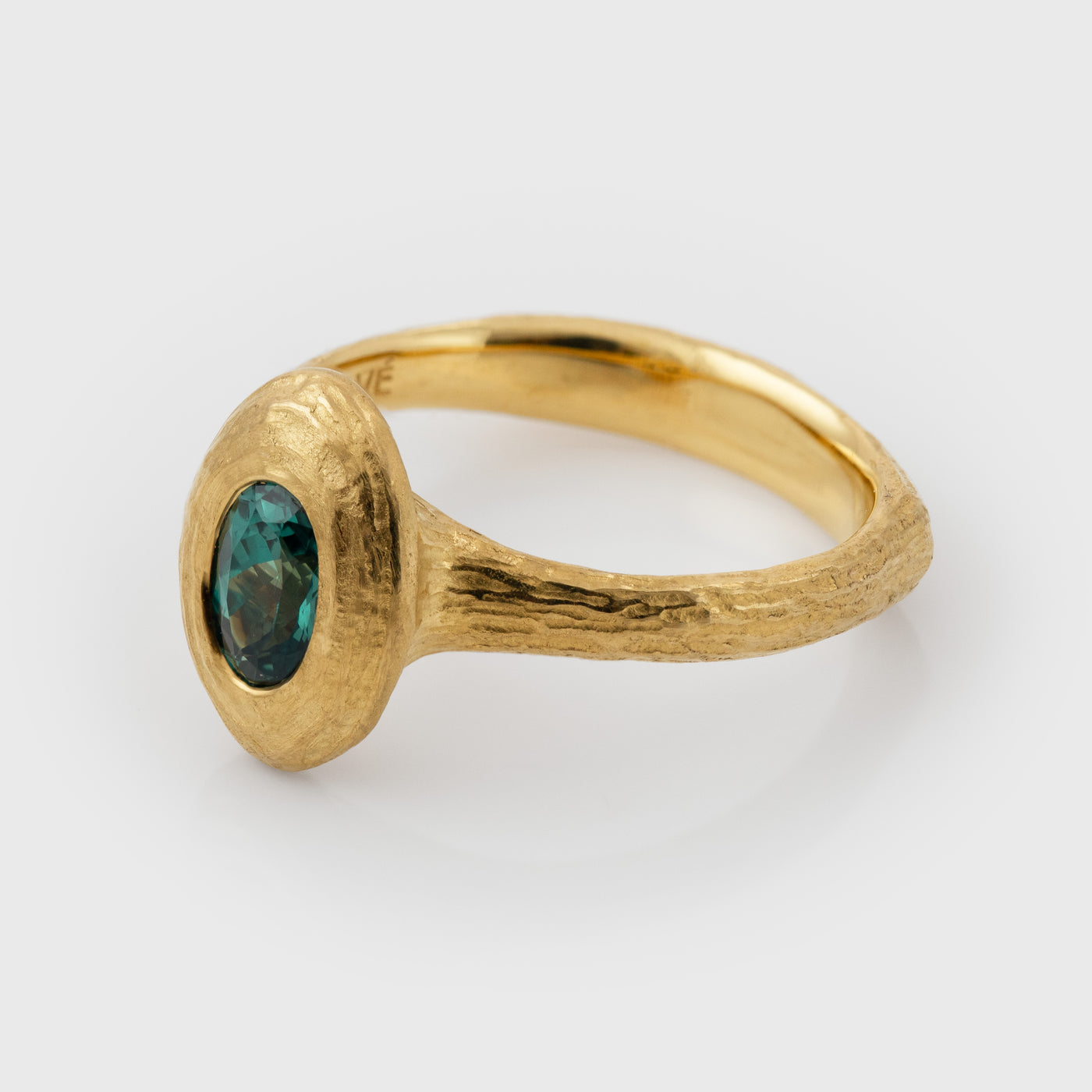 Side view of gold ring with a green Alexandrite gemstone on a white background