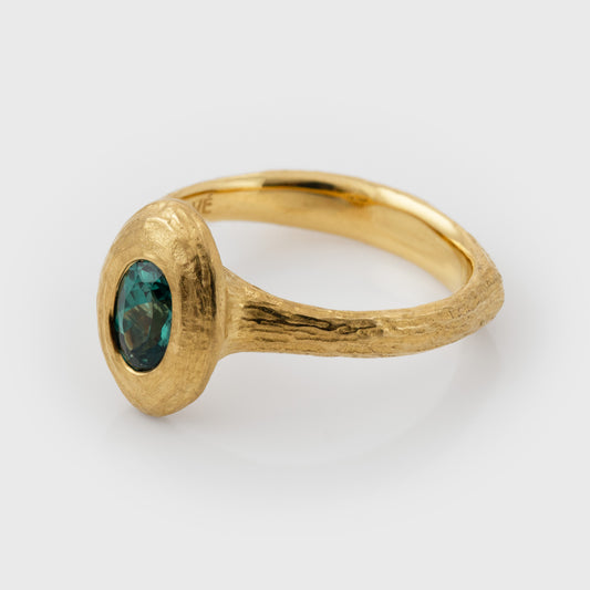 Side view of gold ring with a green Alexandrite gemstone on a white background