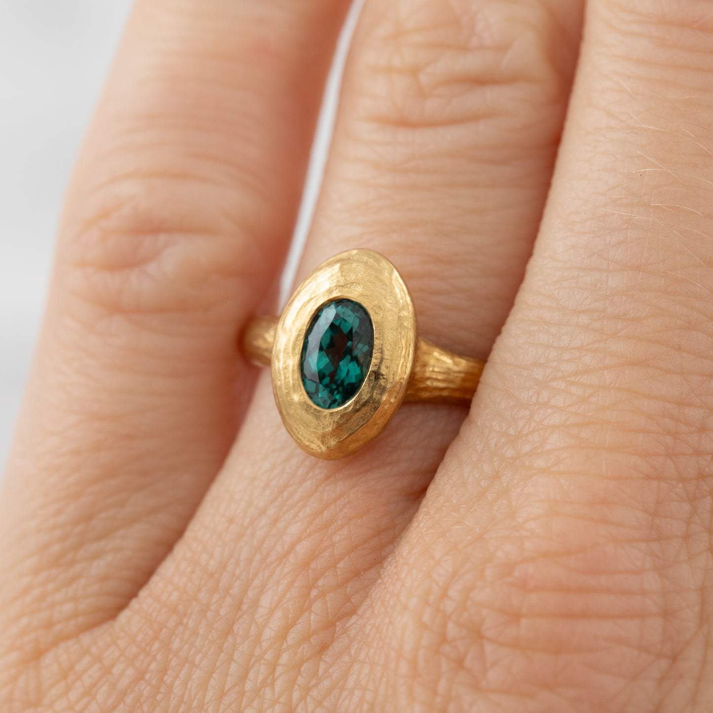 Gold ring with a green Alexandrite gemstone on a hand