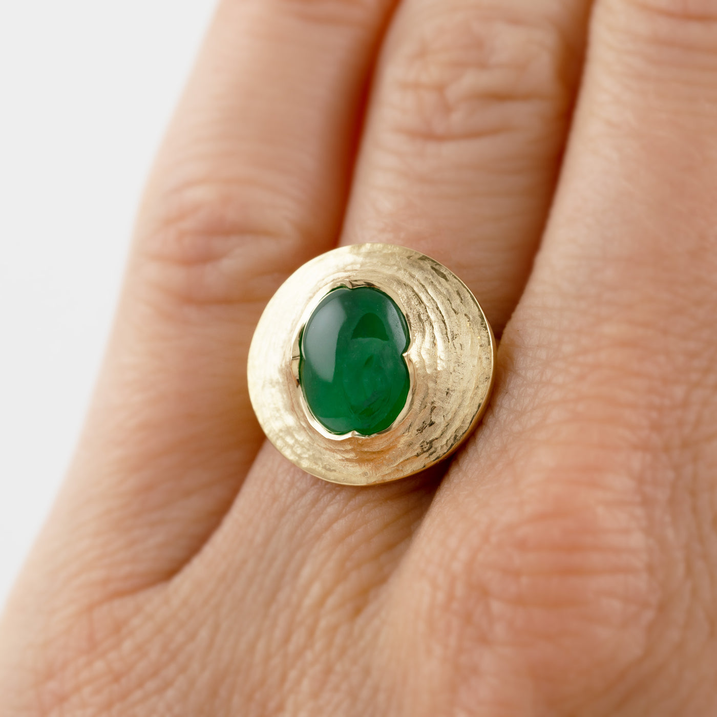 Yellow gold ring featuring oval cabochon green Jade worn on a hand