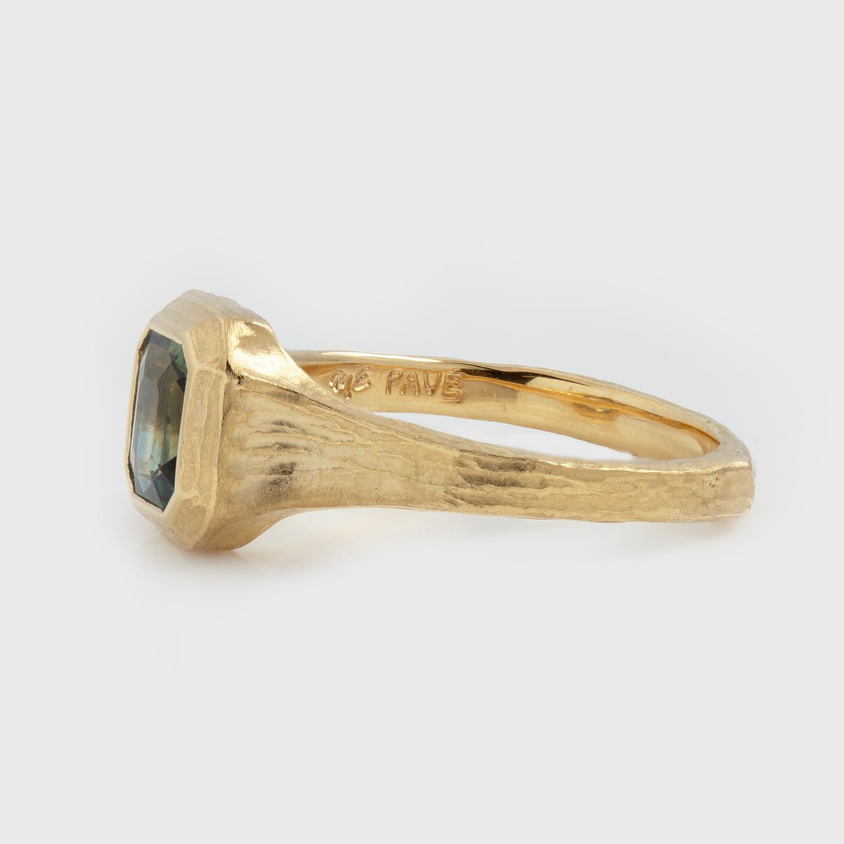 Side view of yellow gold ring featuring a blue and green sapphire center stone with a textured band, photographed on a white background. Side ring reads PAVE and ME
