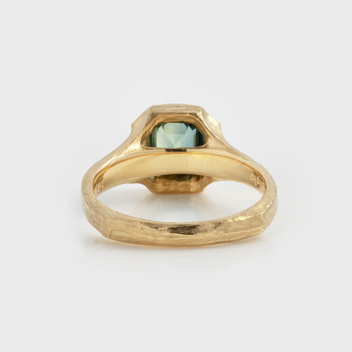 Rear angle of yellow gold ring featuring a blue and green sapphire center stone with a textured band, photographed on a white background.
