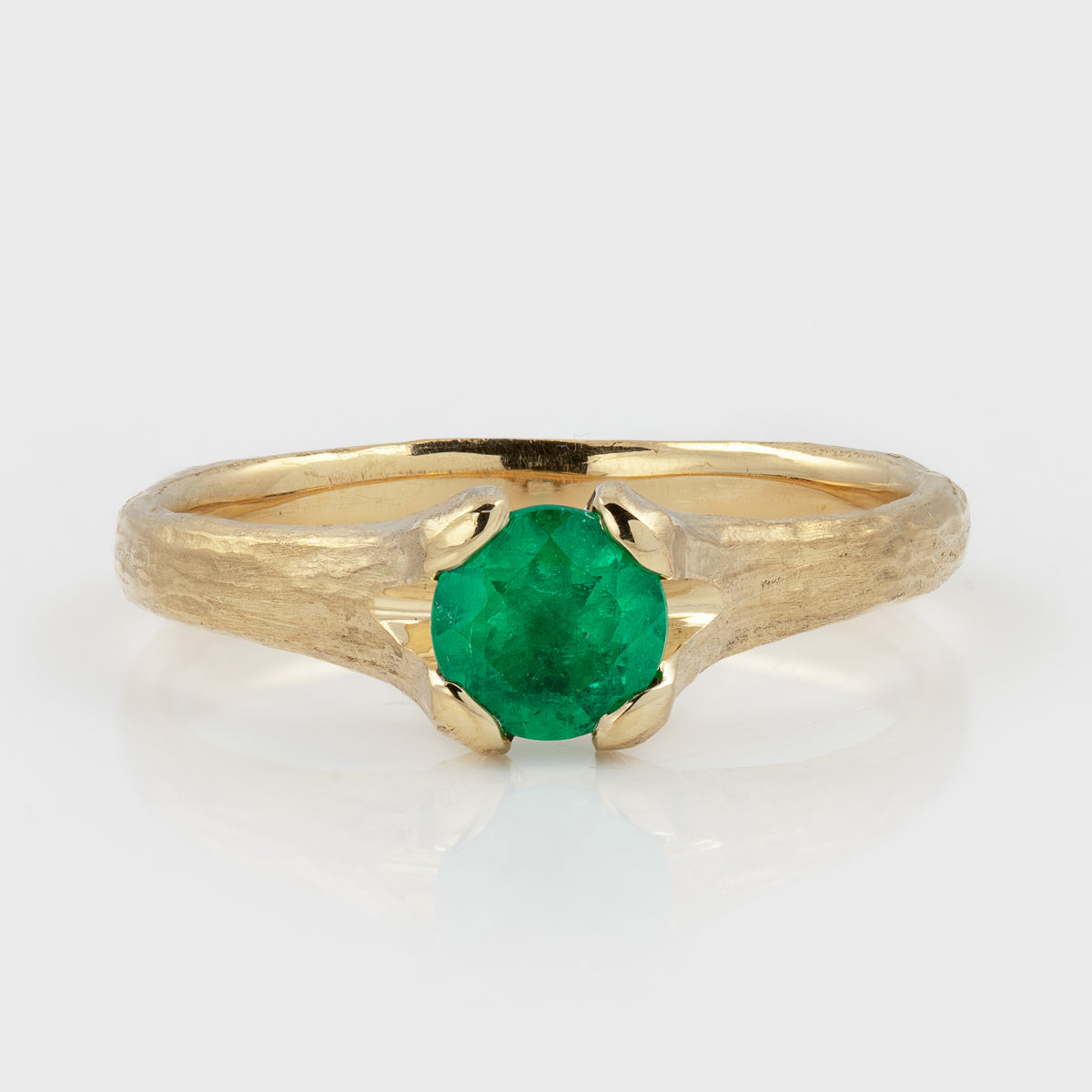 Yellow gold ring featuring a round green stone and a textured band, photographed on a white background.