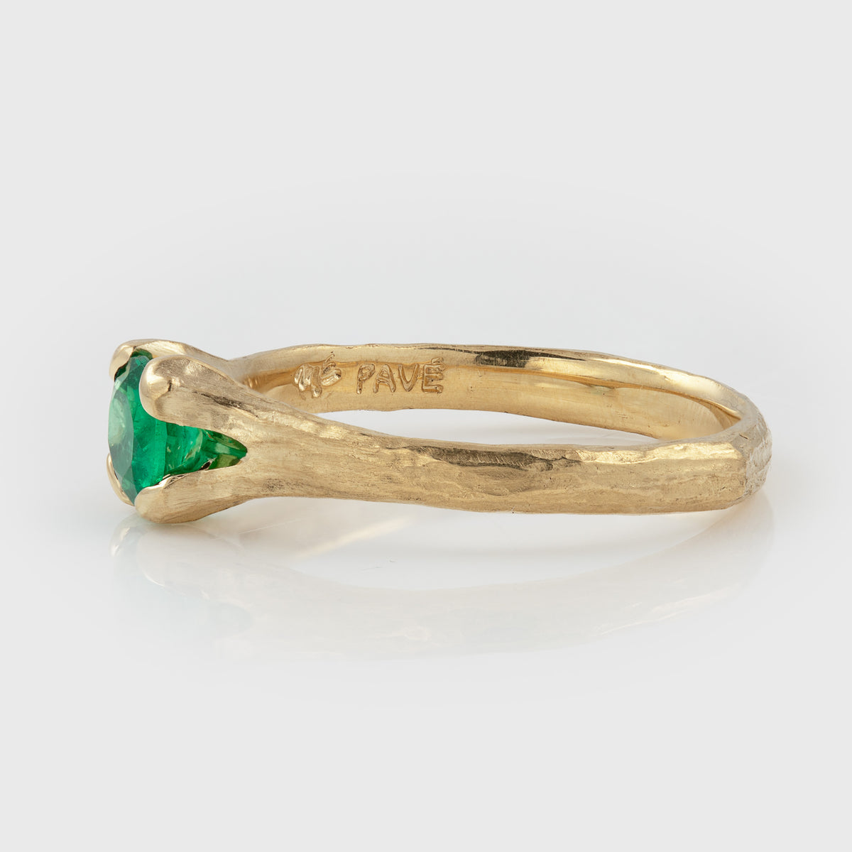 Side view of a gold ring featuring a round green stone and a textured band, photographed on a white background. Side of ring has engraved text that reads PAVE and ME