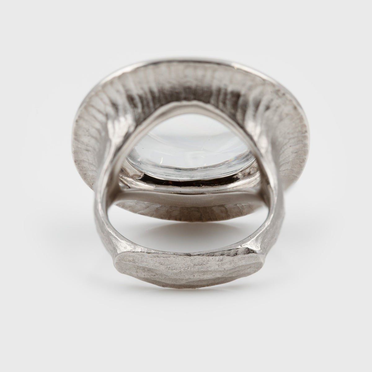 Back of white platinum  ring with a large clear, center stone and a wide textured band, photographed against a white background.
