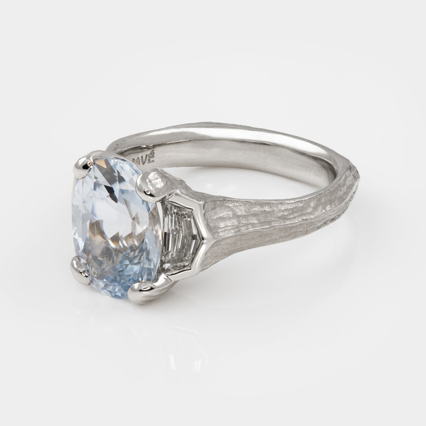 Side angle of platinum ring with a large blue gemstone on a white background