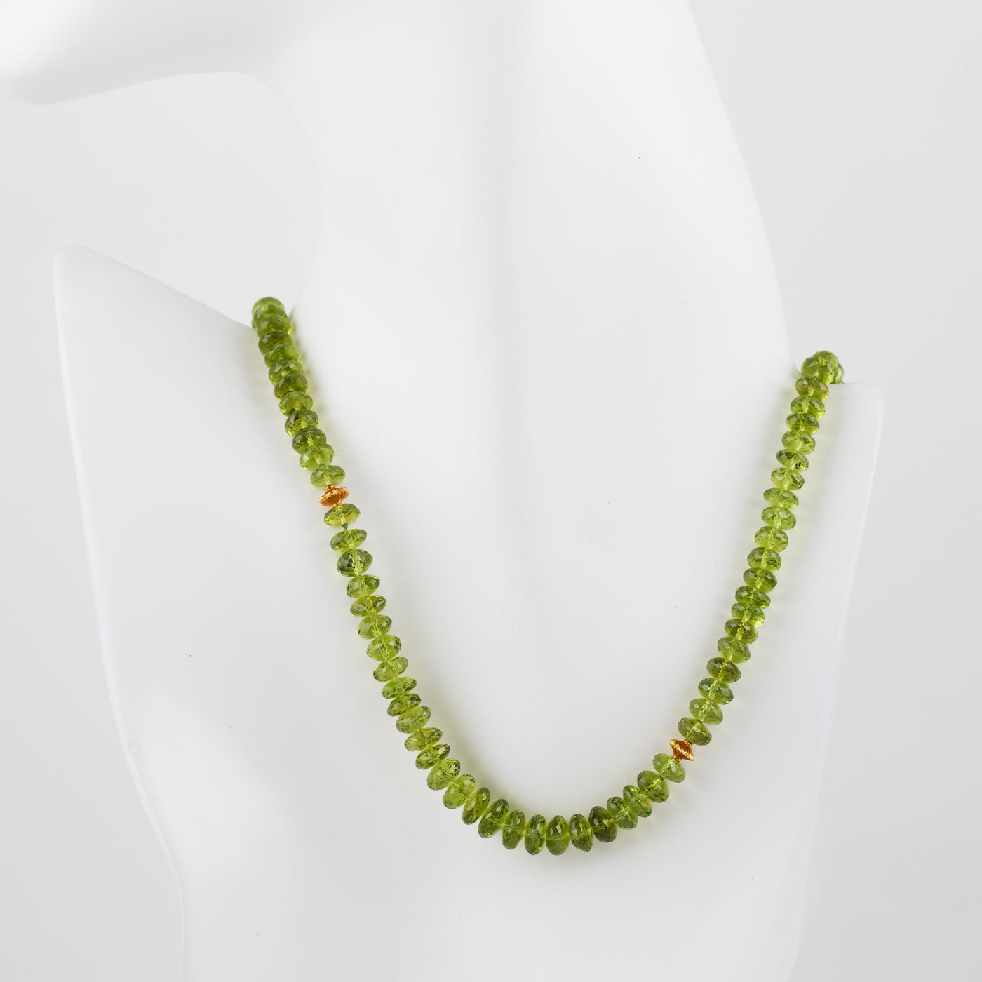Peridot beaded necklace with gold accent beads on a mannequin bust on a white background