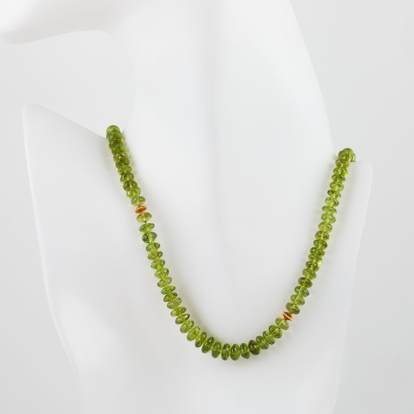Peridot beaded necklace with gold accent beads on a mannequin bust on a white background