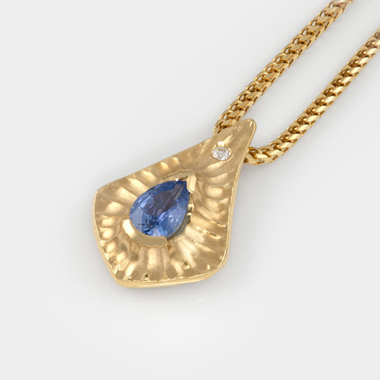 Gold pendant with a blue gemstone on a white background