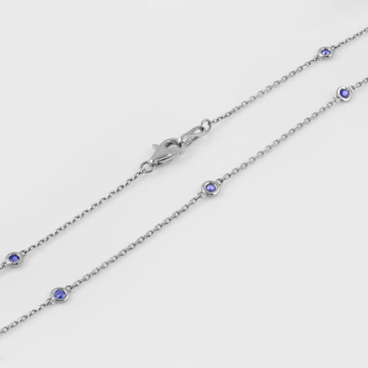 Close-up of 14k white gold station necklace featuring 10 faceted round blue Sapphires and a lobster clasp.