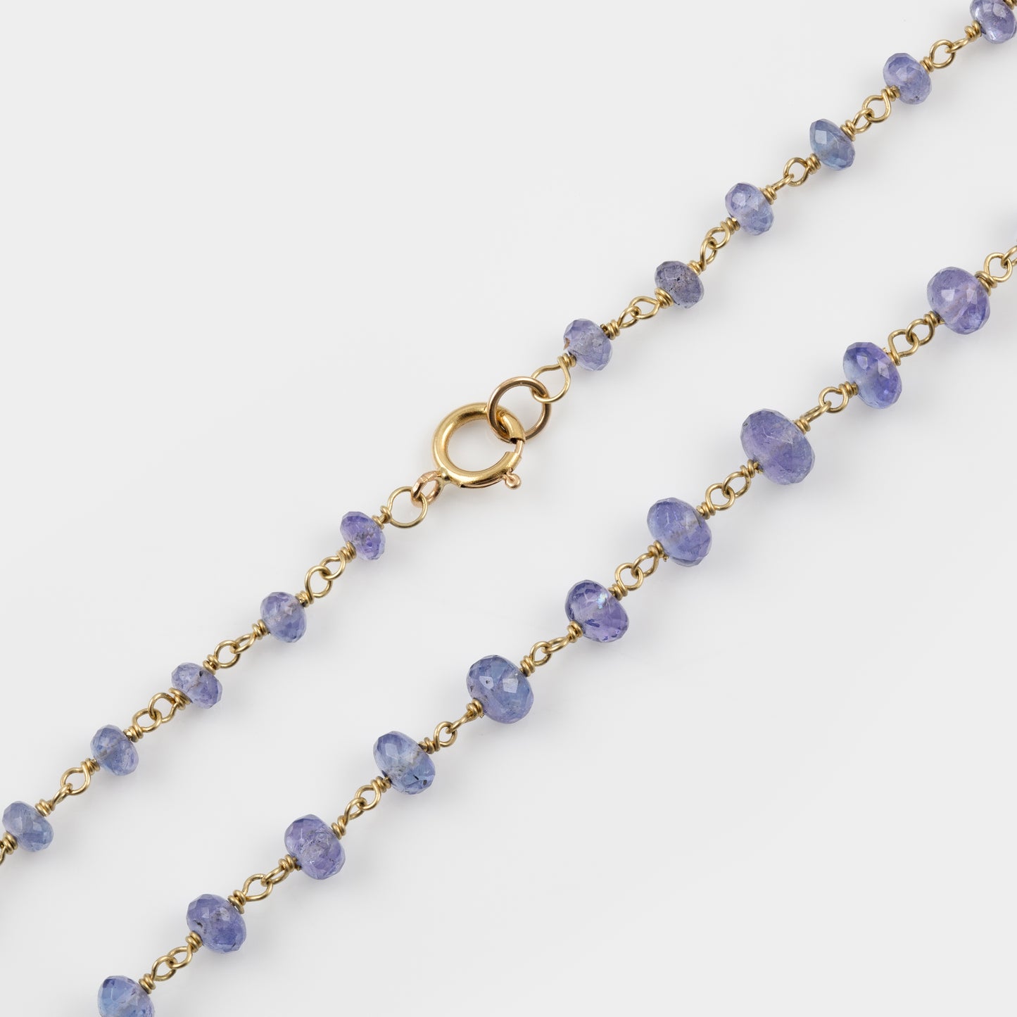 Necklace with Tanzanite beads and gold chain on a white background