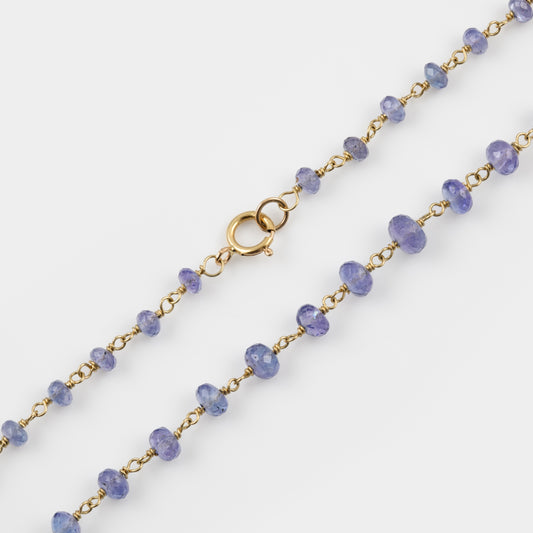 Necklace with Tanzanite beads and gold chain on a white background