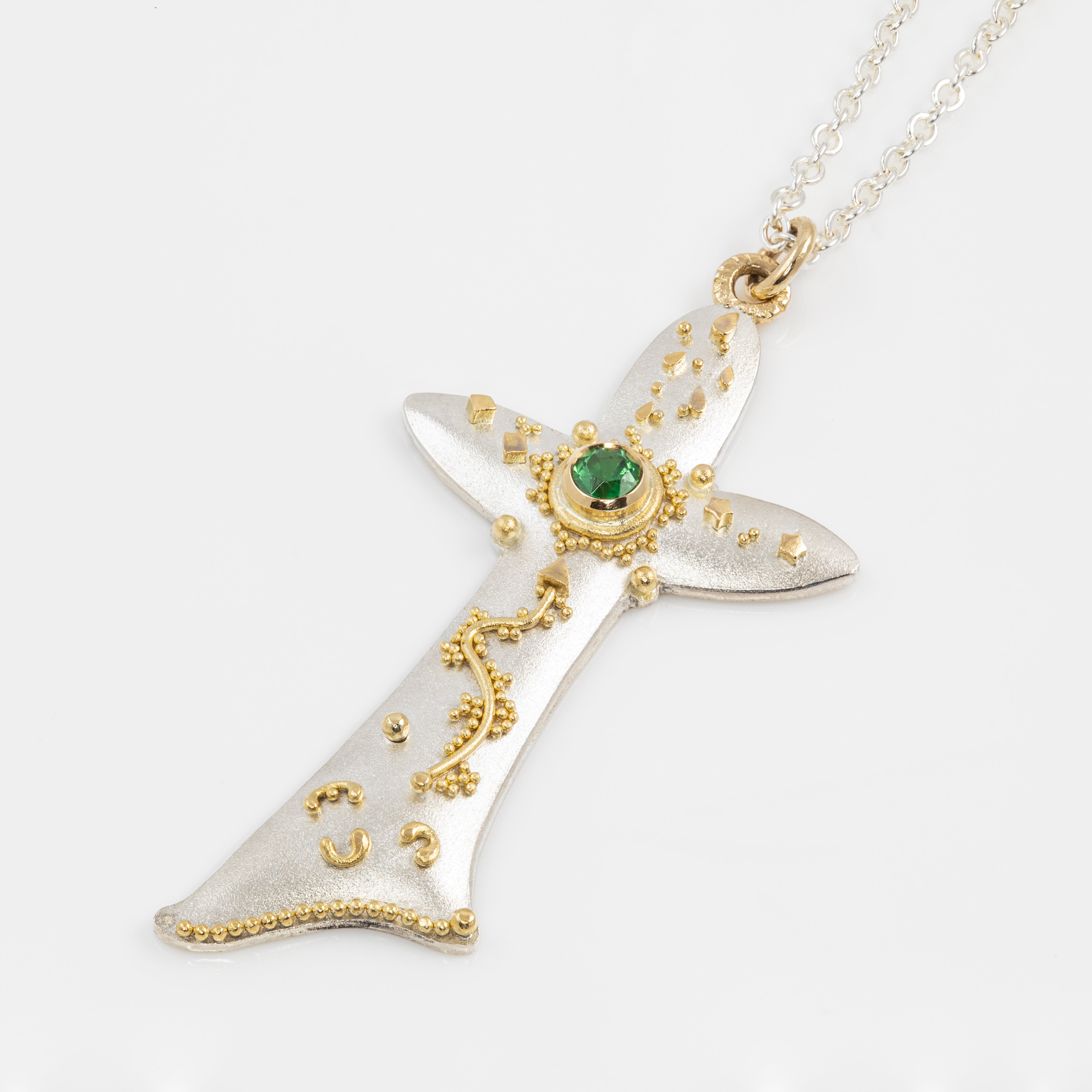 Decorative pendant with gold accents and a green gemstone on a white background