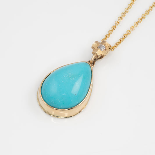 14K yellow gold and turquoise pendant on a gold chain against a white background