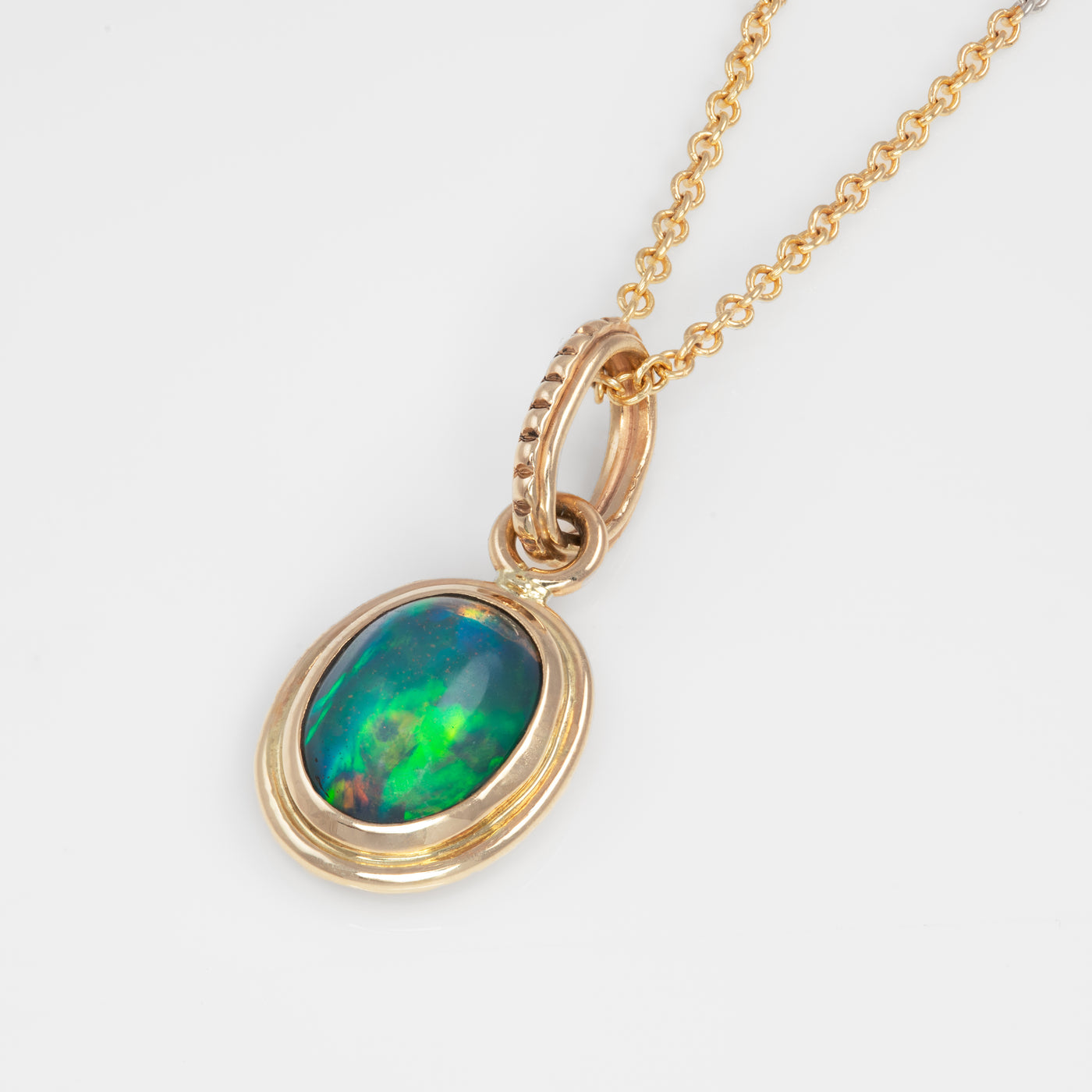 Gold pendant with green and blue opal stone on a white background