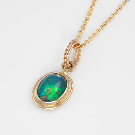 Gold pendant with green and blue opal stone on a white background