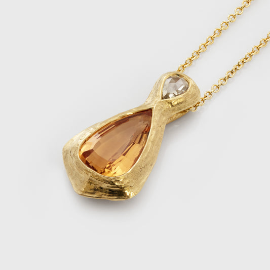 Gold necklace with a yellow orange topaz gemstone and an accent diamonds on a white background