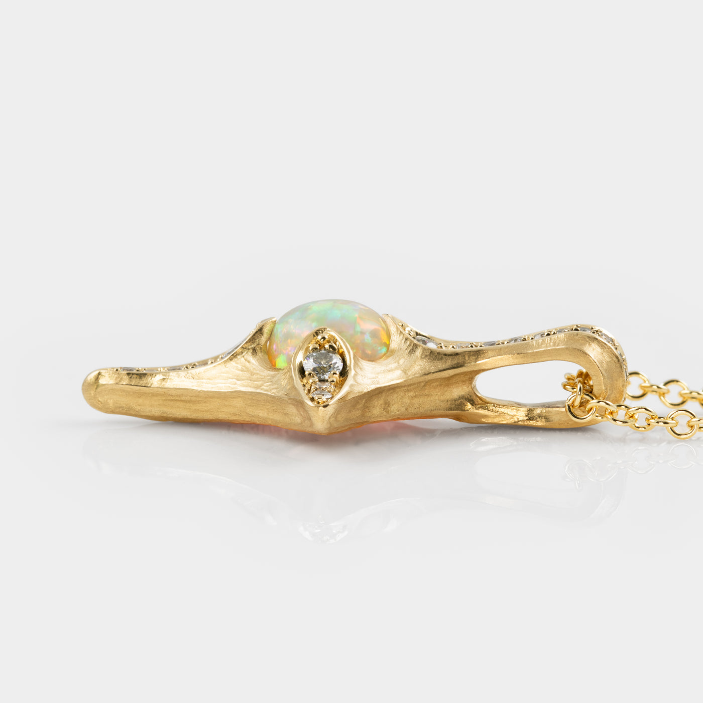 Gold necklace with an opal and diamond pendant on a white background