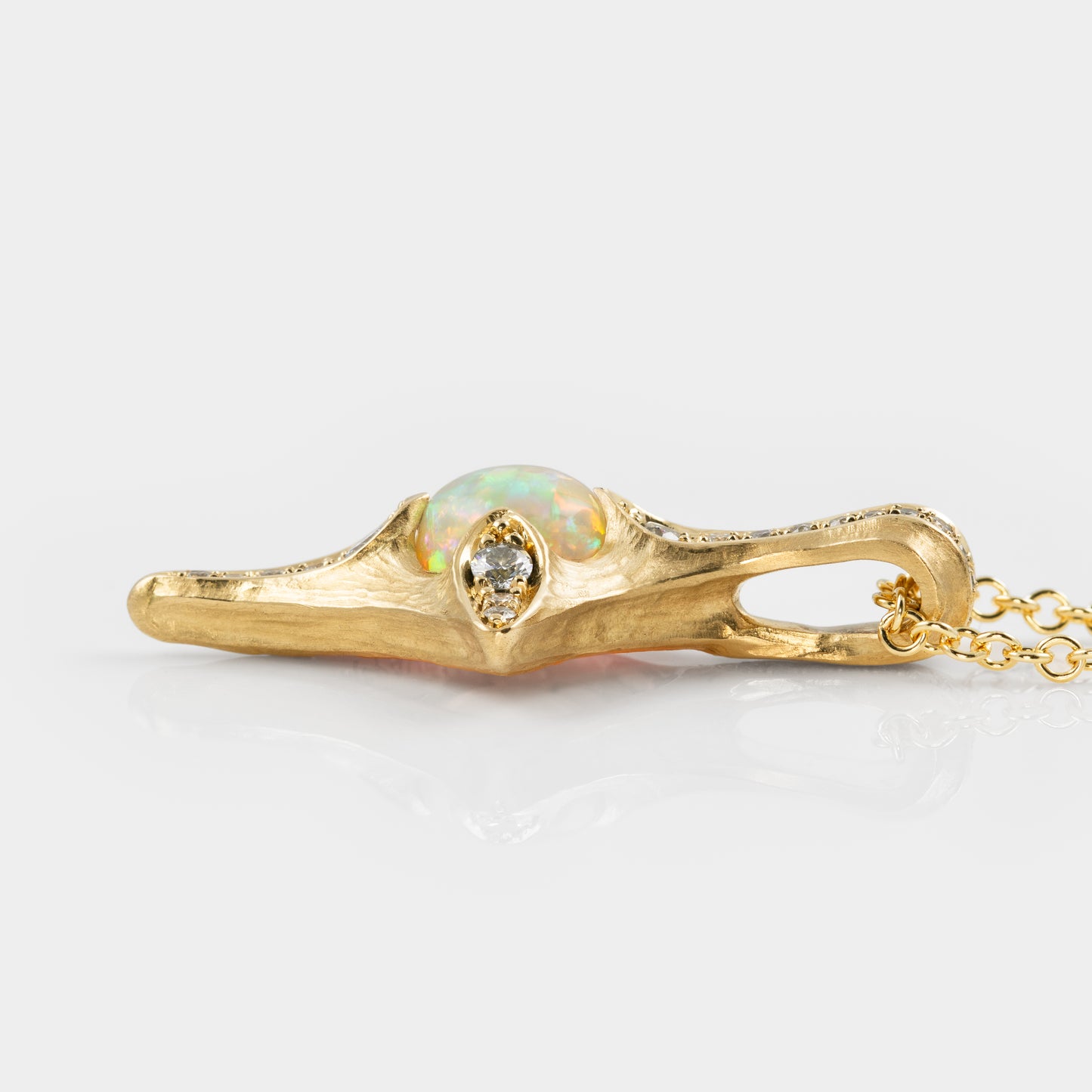 Gold necklace with an opal and diamond pendant on a white background