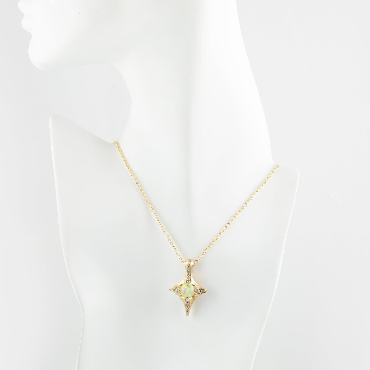Gold necklace with a opal pendant on a mannequin bust against a white background