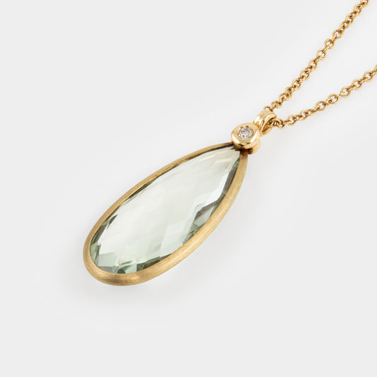 Gold necklace with a green teardrop pendant on a white background