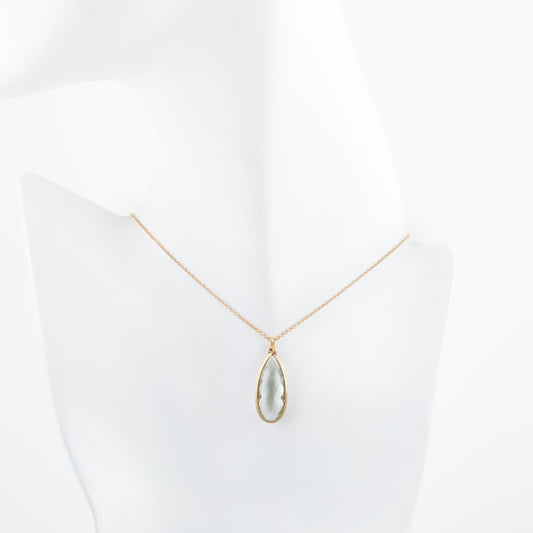 Gold necklace with a teardrop-shaped pendant on a white mannequin