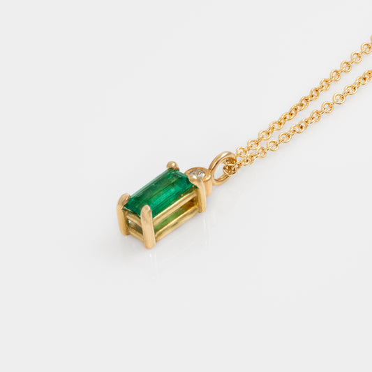 Gold necklace with a green gemstone pendant on a white background