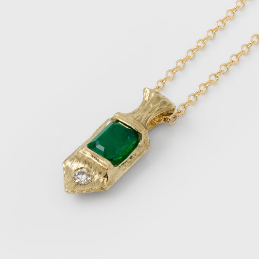 Gold necklace with a green emerald gemstone pendant on a white background