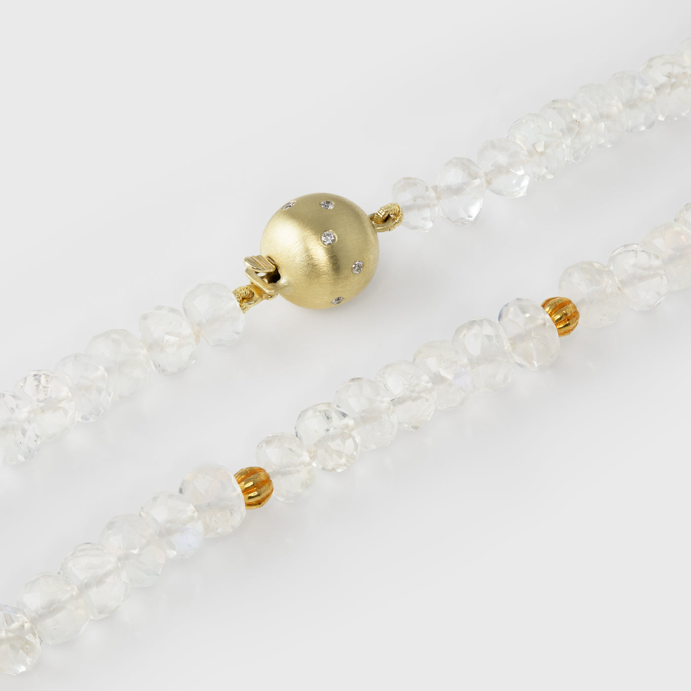 Close-up of a moonstone beaded necklace with a gold clasp on a light background