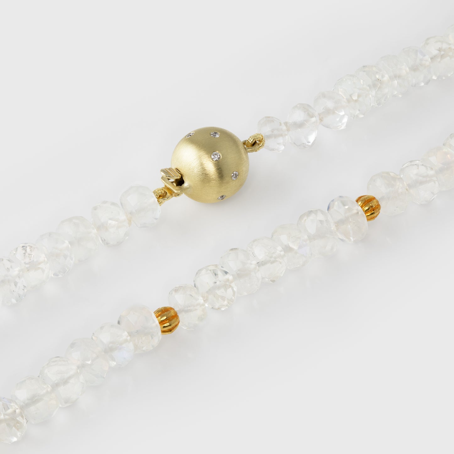 Close-up of a moonstone beaded necklace with a gold clasp on a light background
