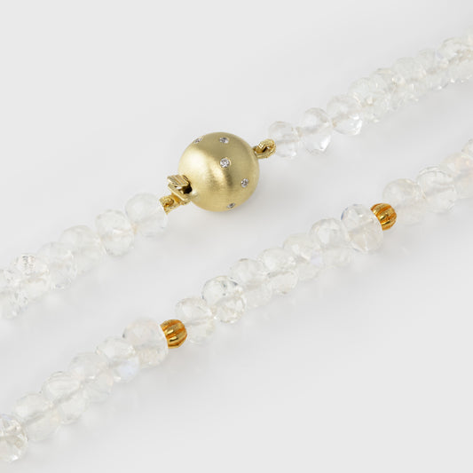 Close-up of a moonstone beaded necklace with a gold clasp on a light background