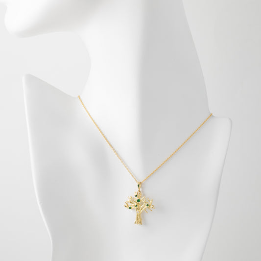 Gold necklace with a tree pendant on a mannequin bust.