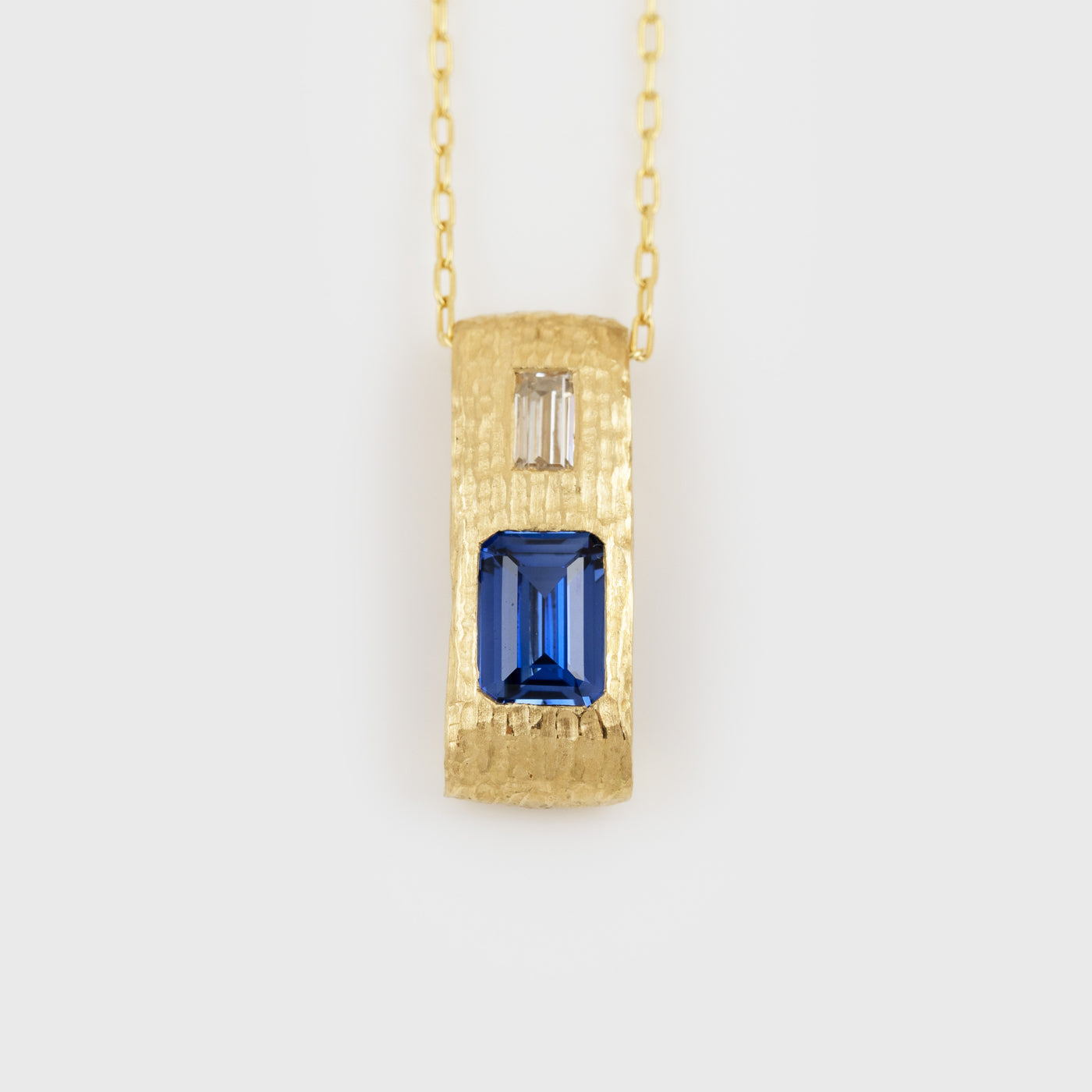 Yellow gold pendant feauturing emerald cut blue Sapphire and baguette cut Diamond