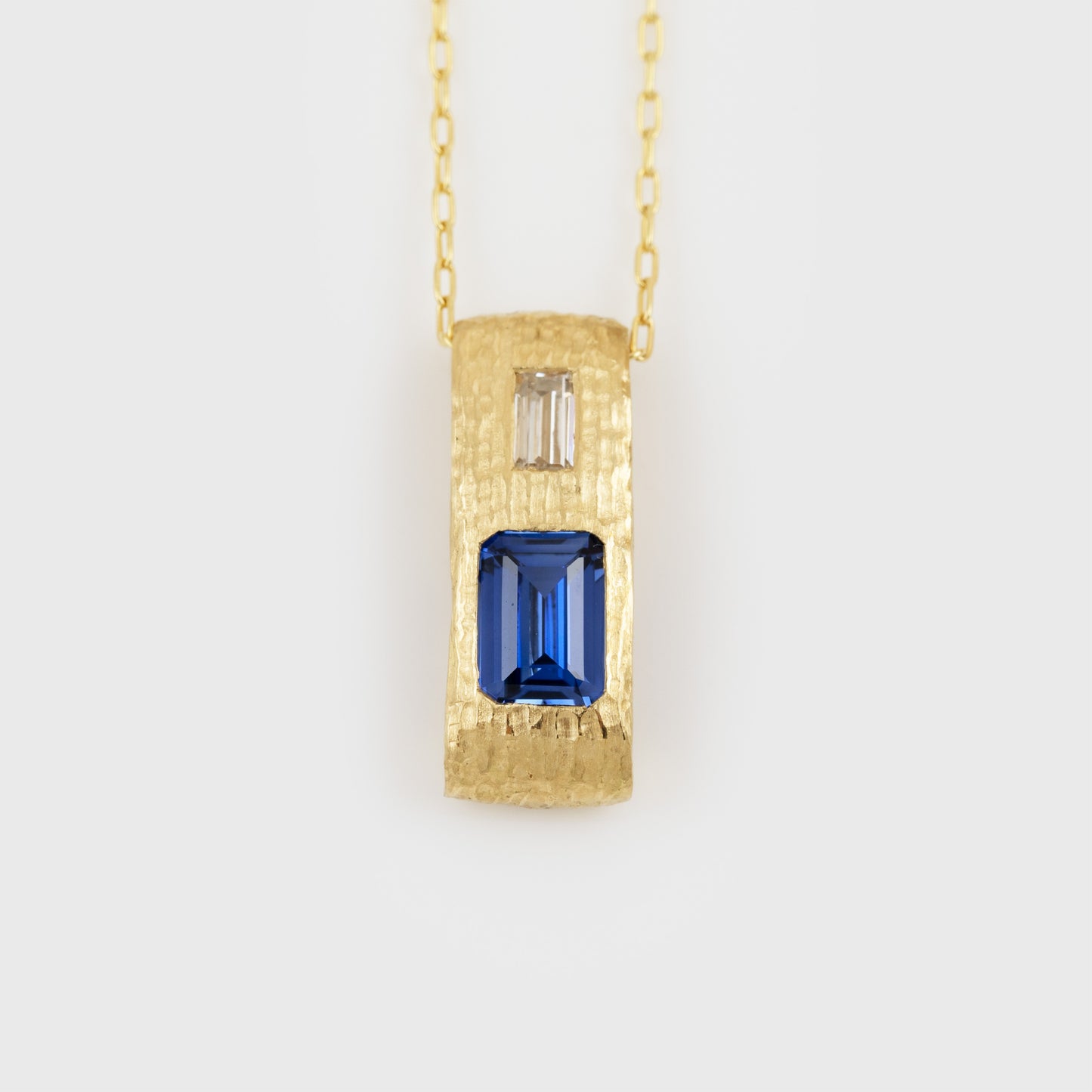 Yellow gold pendant feauturing emerald cut blue Sapphire and baguette cut Diamond