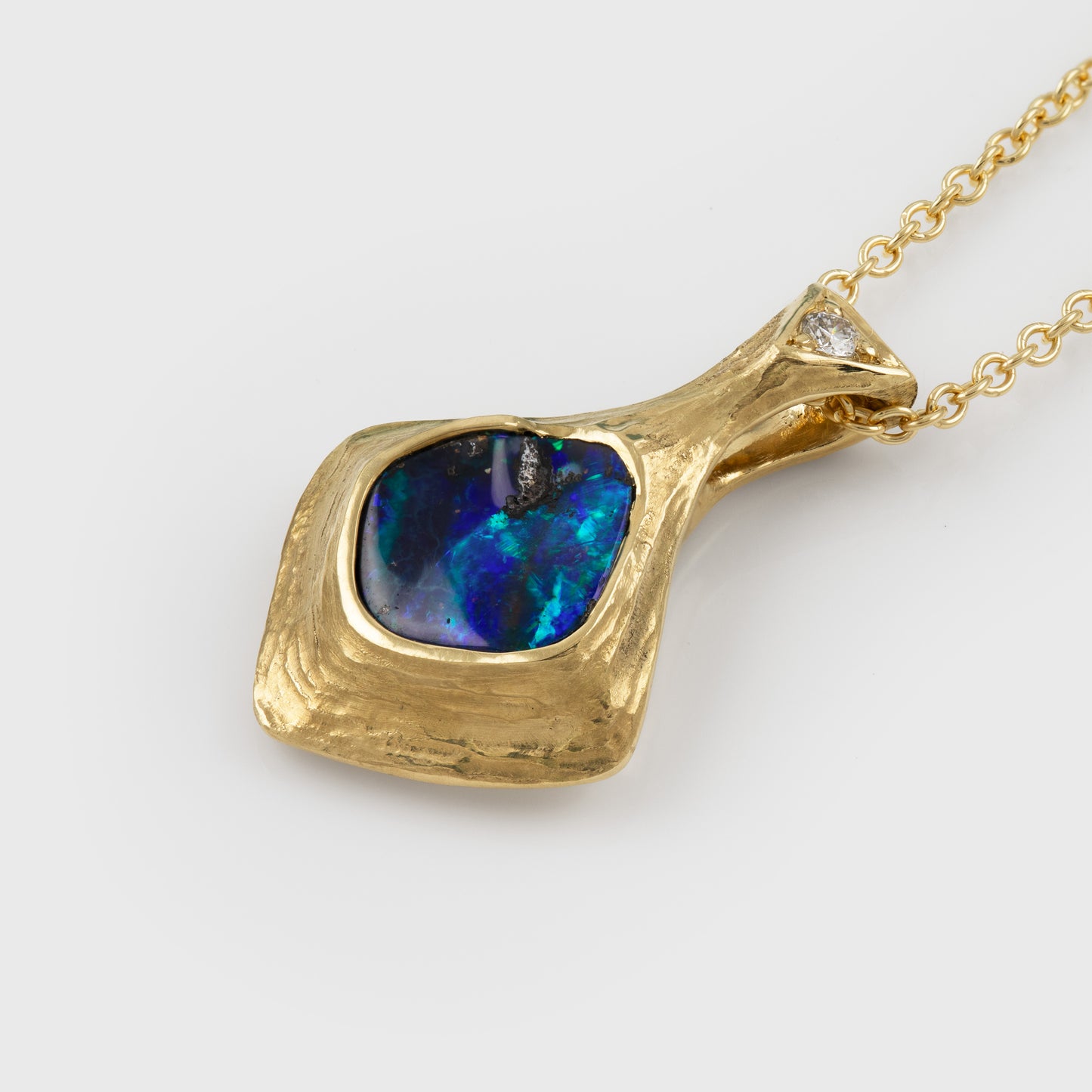Gold natural texture necklace with a blue and green opal gemstone and accent diamond on a white background