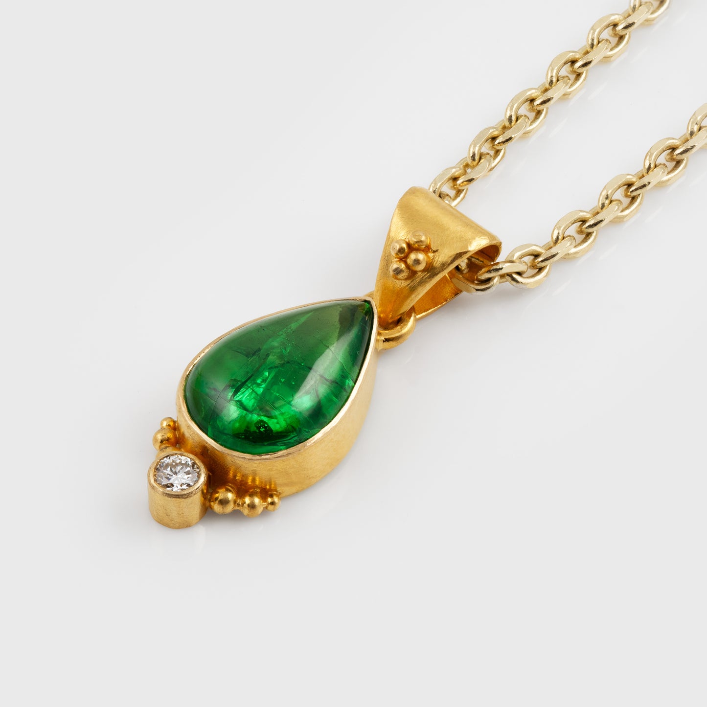 Gold necklace with a green gemstone on a white background