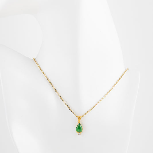 Gold necklace with a green gemstone on a white mannequin