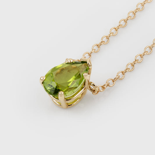 A yellow gold necklace featuring a teardrop-shaped green peridot gemstone pendant, shown on a clean white background.