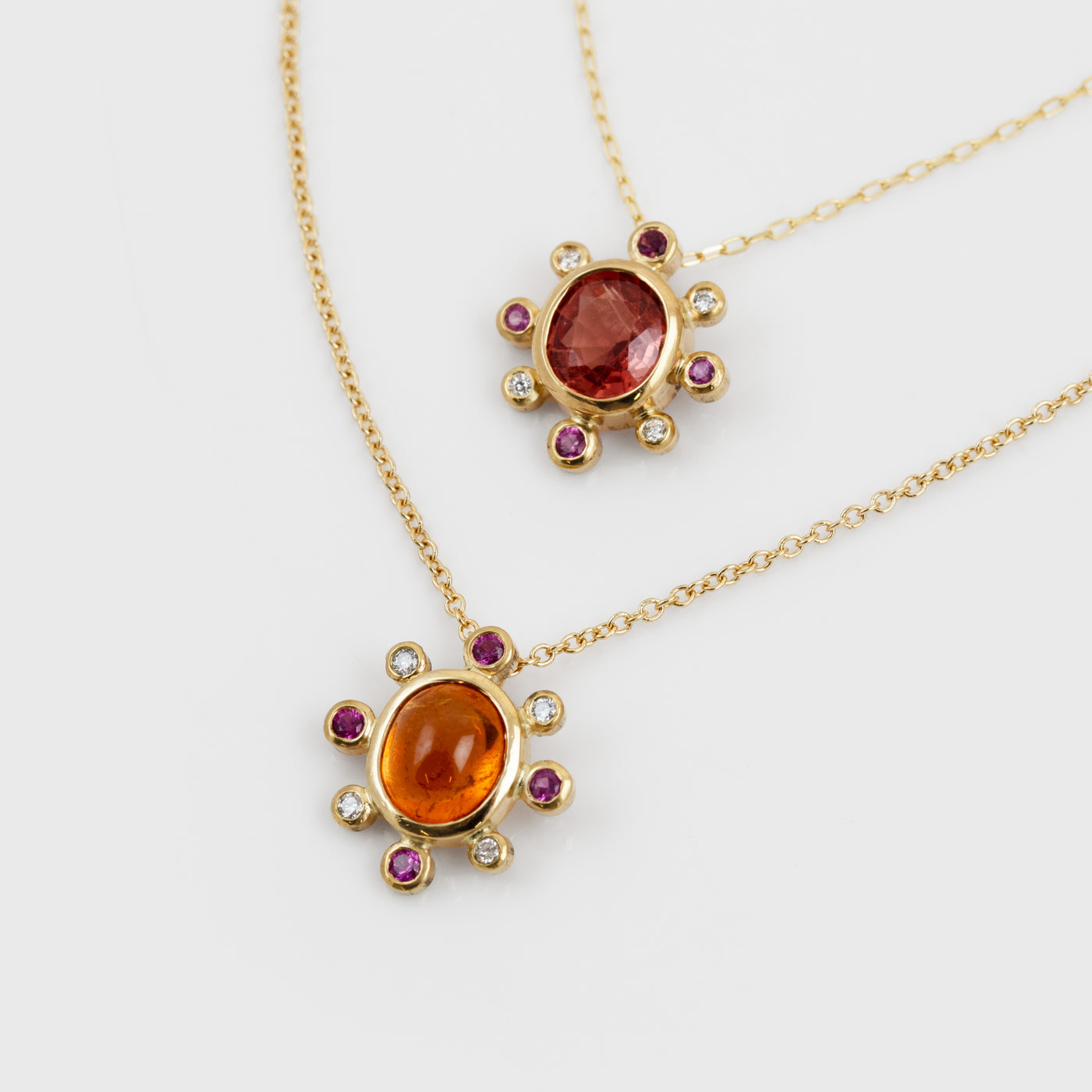 Two yellow gold necklaces with assorted orange, red, pink, and white gemstones
