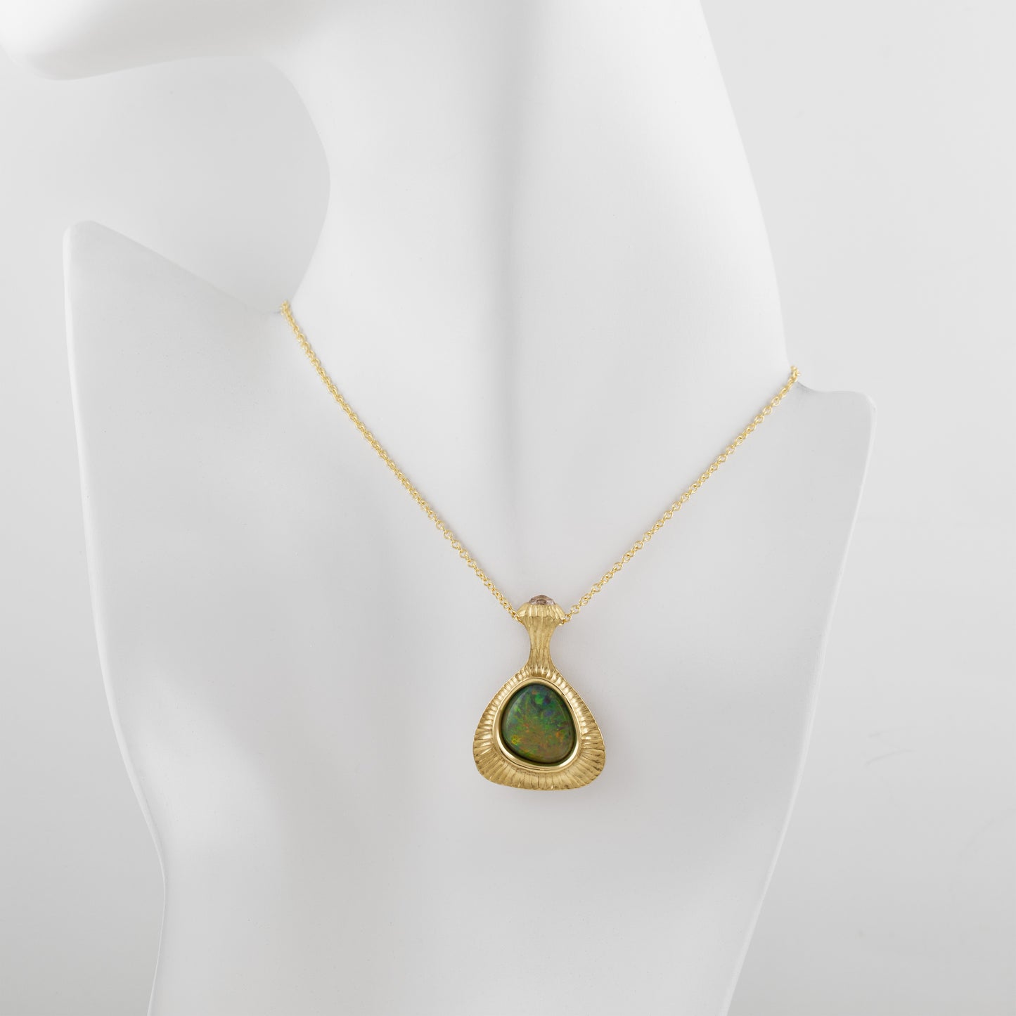Yellow gold pendant featuring bezel set Opal suspended from chain on faux model neck