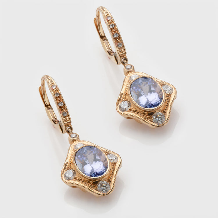 Close-up of 14 karat yellow gold earrings with tanzanite and diamonds.