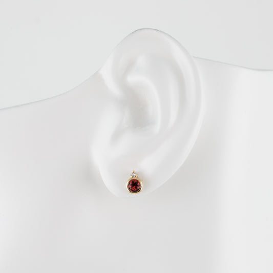 A single gold stud earring with a small red spinel gemstone displayed on a white ear mannequin against a clean white background.
