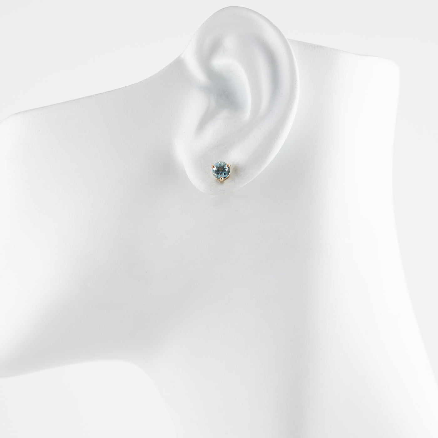 Aquamarine earring on a mannequin ear with a plain background