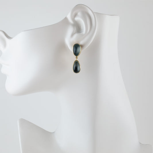 A pair of gold drop earrings with dark gray teardrop-shaped stones, displayed on a white mannequin head against a light gray background.
