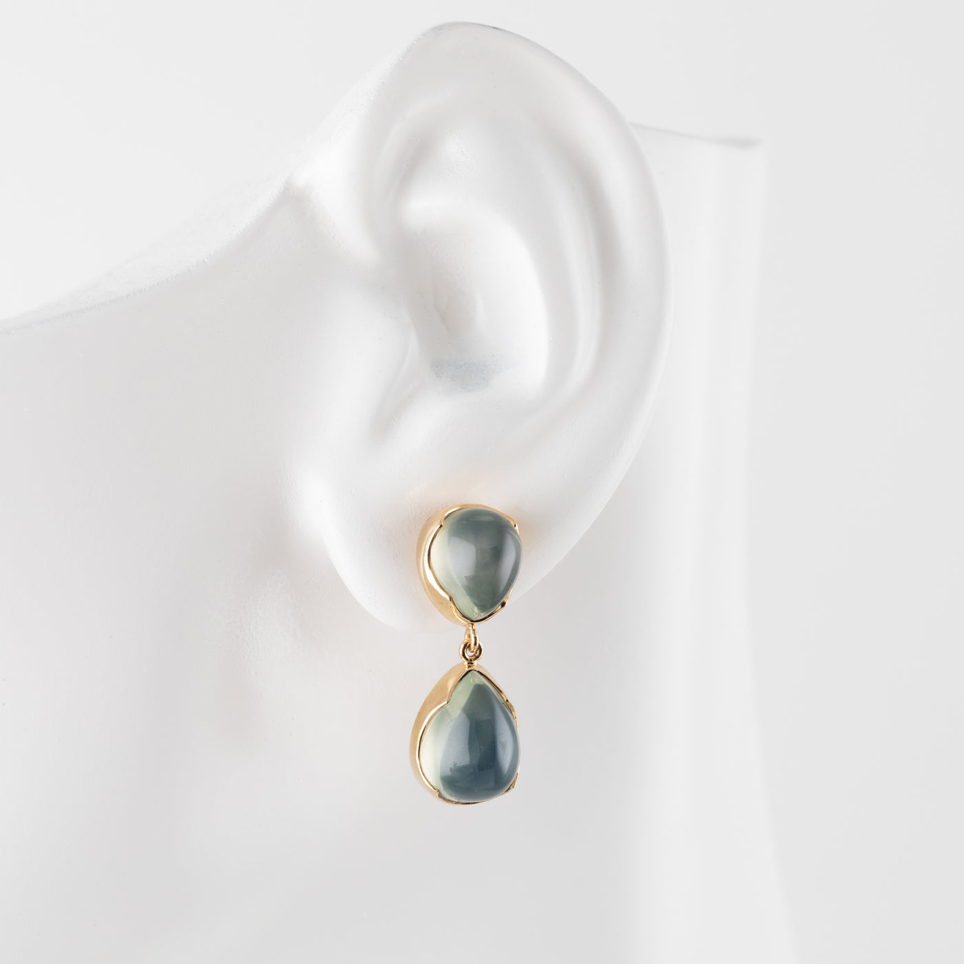 Green moonstone gemstone earrings on a white mannequin ear