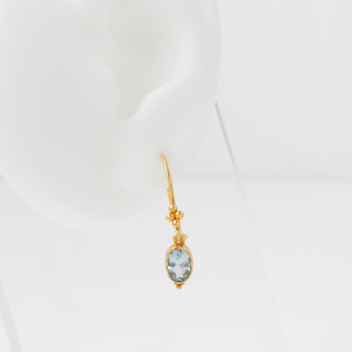 Gold earring with a gemstone on a white background