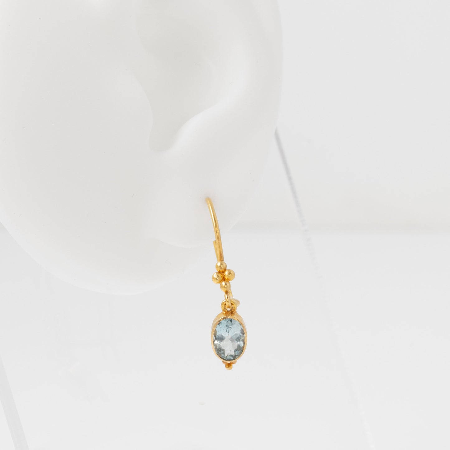 Gold earring with a gemstone on a white background