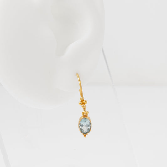 Gold earring with a gemstone on a white background